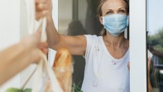 woman-with-medical-mask-picking-up-her-groceries-in-self-isolation