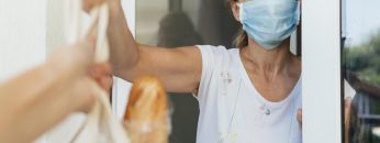 woman-with-medical-mask-picking-up-her-groceries-in-self-isolation